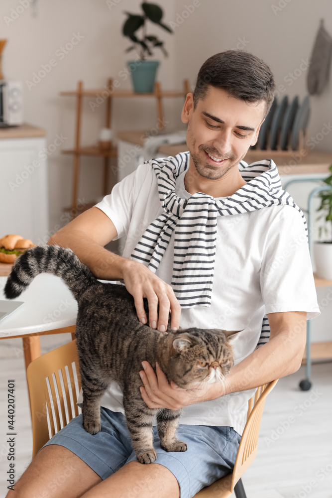 年轻人带着可爱的猫在厨房