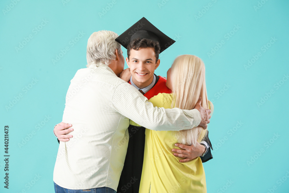 快乐的男毕业学生和他的父母在彩色背景上