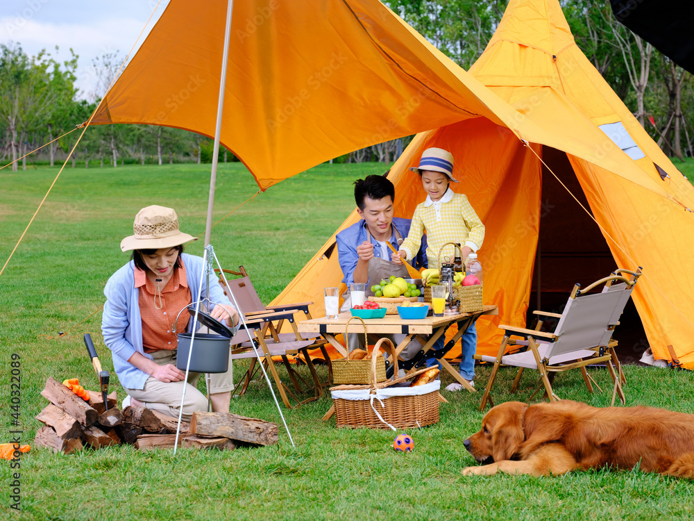 Happy family of three and pet dog cooking outdoors