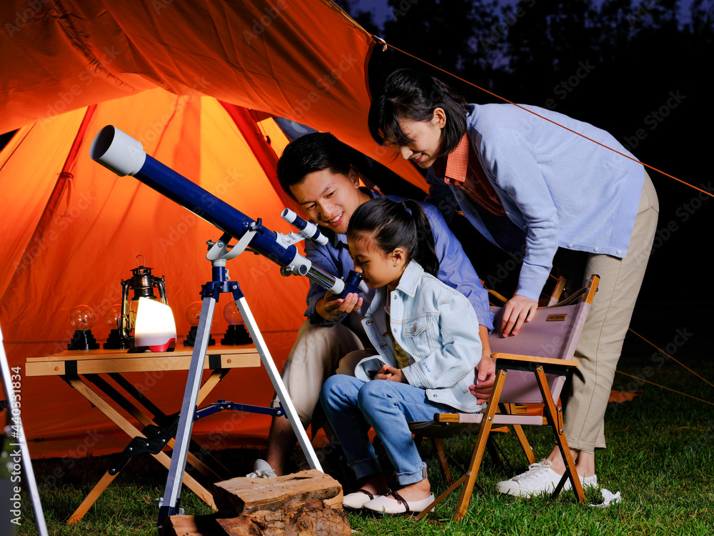 一个幸福的三口之家在户外使用望远镜