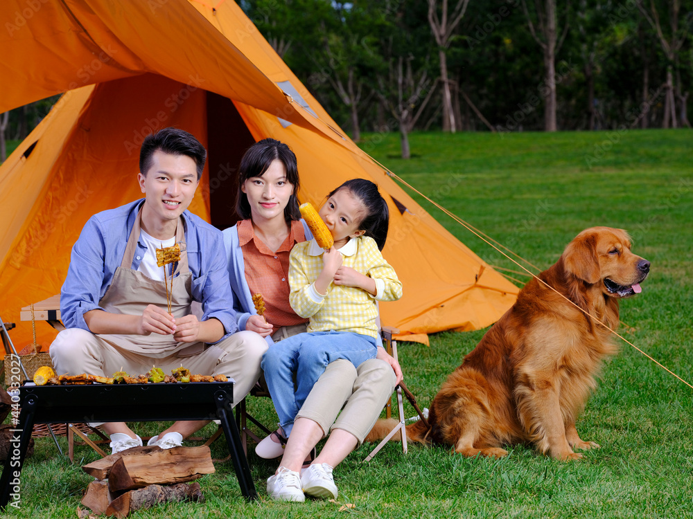 Happy family of three and pet dog barbecue in the park
