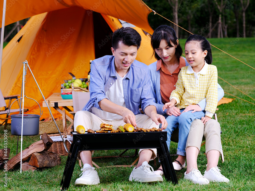 A happy family of three barbecue in the park