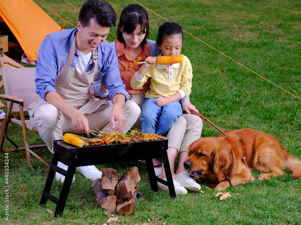 快乐的三口之家和公园里的宠物狗烧烤