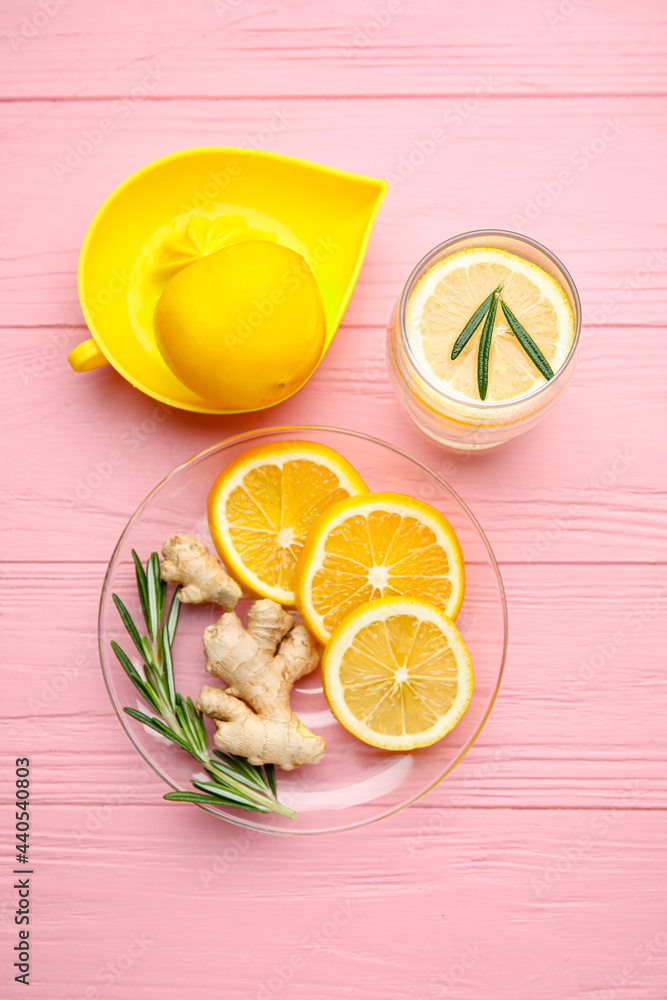 一杯健康的柠檬水和彩色木质背景的挤压器