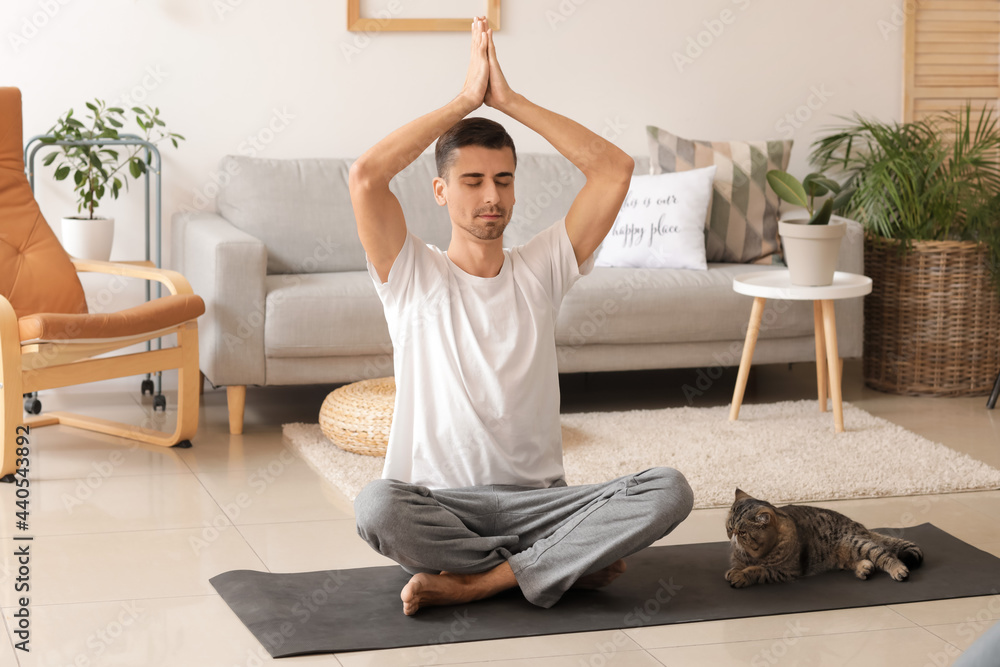 年轻人带着可爱的猫在家练习瑜伽