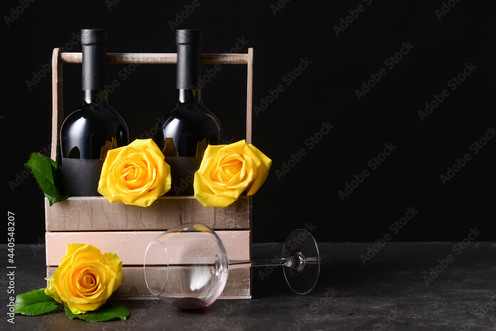 盒子里有酒瓶、漂亮的玫瑰和深色背景的玻璃杯