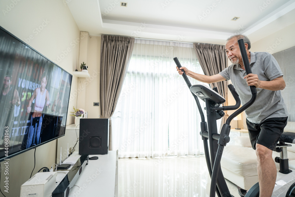 老年人在家使用健身自行车锻炼跟随健身视频