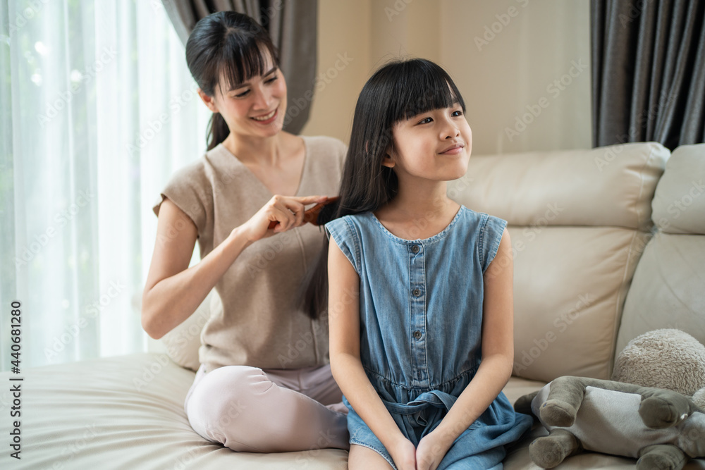 亚洲妈妈在家用发刷给小孩子女儿梳头