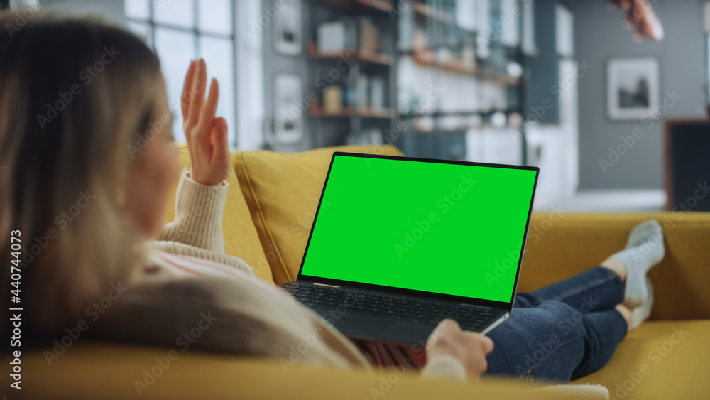 Beautiful Female Specialist Making a Video Call on Laptop with Green Screen Mock Up Display at Home 