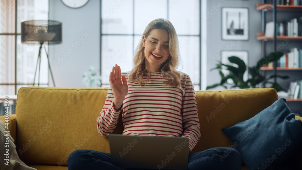 漂亮的女专家坐着在家客厅用笔记本电脑打视频电话
