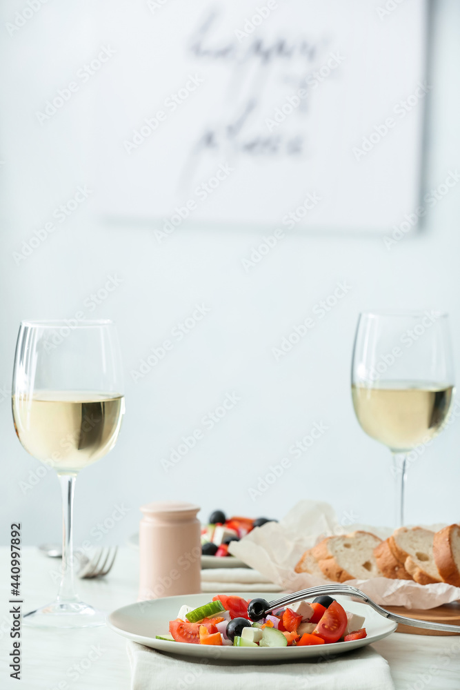 餐厅餐桌上摆着新鲜的希腊沙拉和几杯葡萄酒