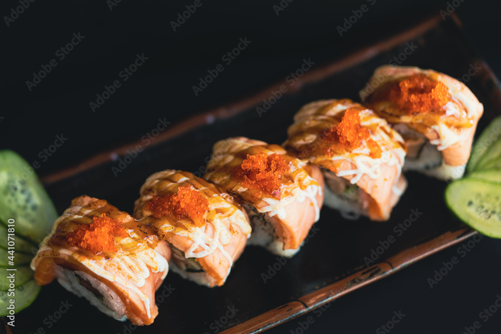 日本餐厅的三文鱼刺身和卷。竹盘上的新鲜三文鱼柳和寿司卷。As