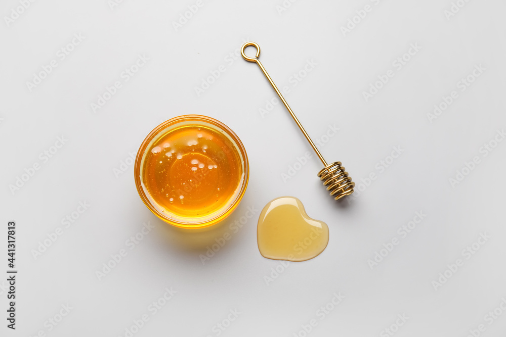 Heart made of honey and dipper on white background