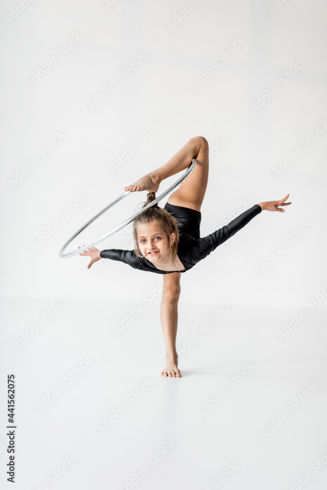 小女孩在白色房间戴着戒指练习艺术体操。儿童体操和训练