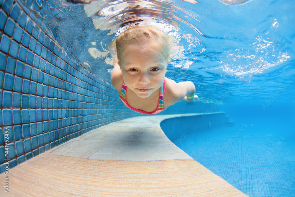 Funny portrait of child learning swimming, dive in blue pool with fun - jumping deep down underwater