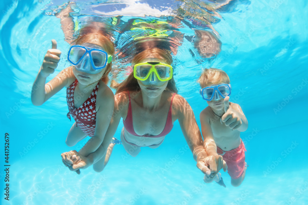 快乐的人们在水下潜水很有趣。母亲和孩子们戴着浮潜面具在水上公园的有趣照片