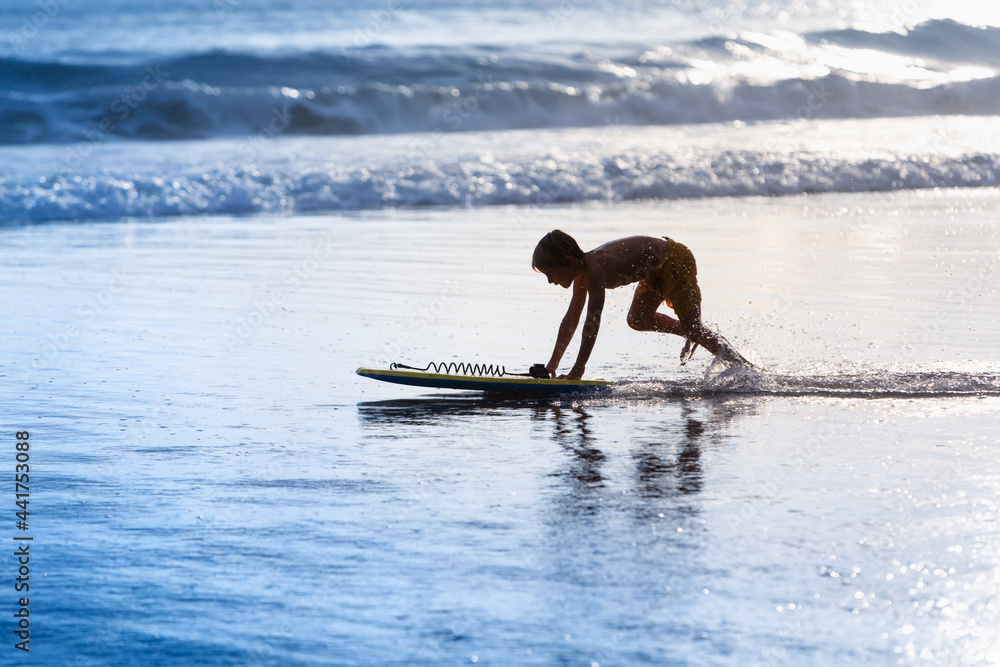 快乐男孩-带着冲浪板的年轻冲浪者在海滩上玩得很开心，在海水池边跑步。活跃的家庭生活
