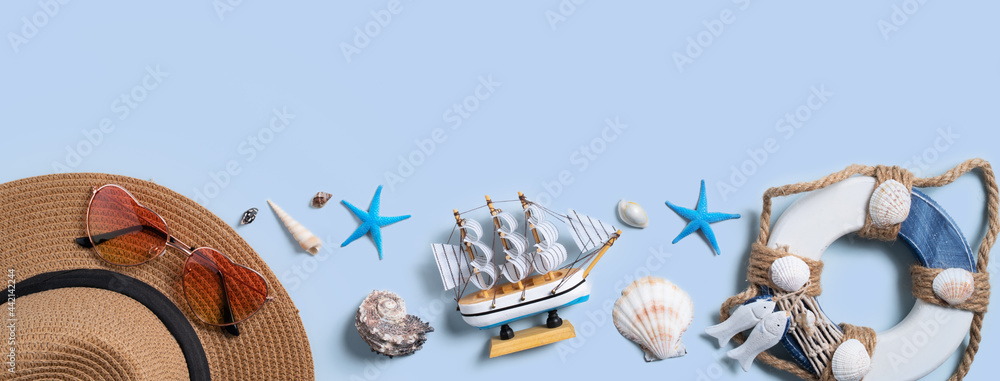 蓝色背景下的贝壳、帽子和太阳镜的夏季海滩背景设计理念。