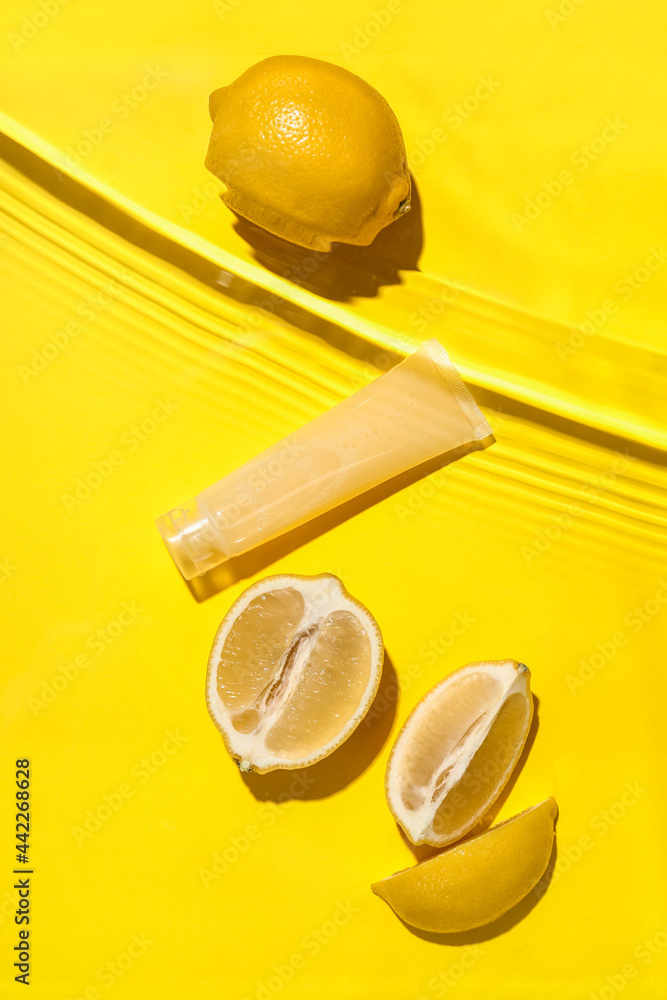 一管化妆品和柠檬在水中的彩色背景