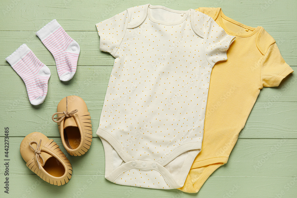 彩色木质背景上的婴儿衣服、鞋子和袜子
