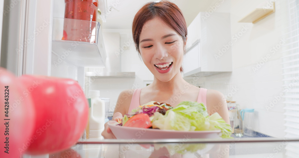woman takes salad from refrigerator