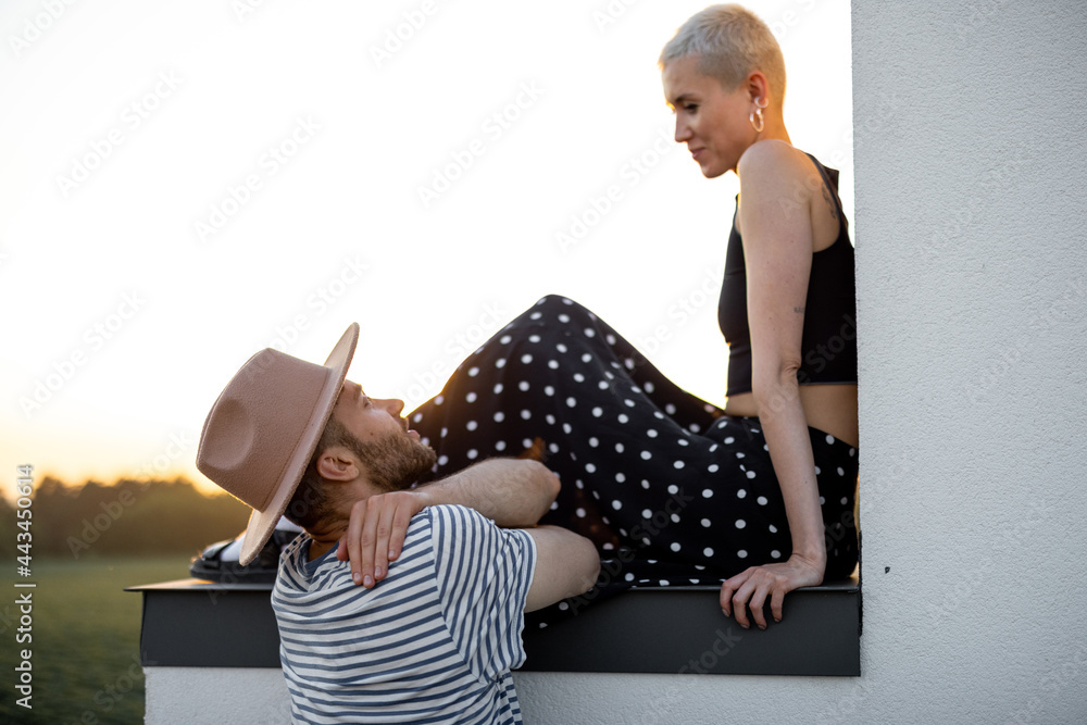 时尚的情侣坐在纳图日落美景的屋顶上亲密交谈