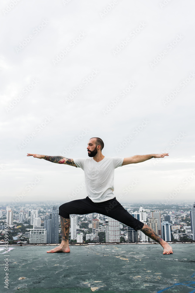 男子在屋顶和城市景观背景下练习瑜伽