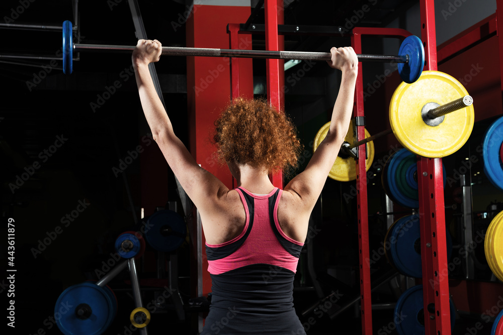 女健美运动员在健身房用杠铃健身