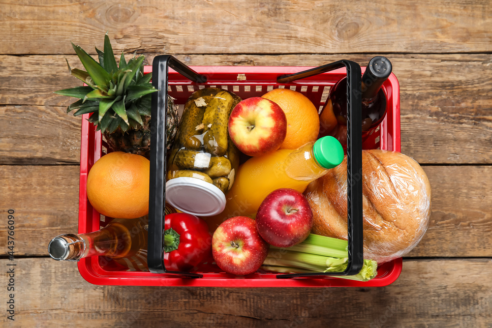 Shopping basket with food on wooden background
