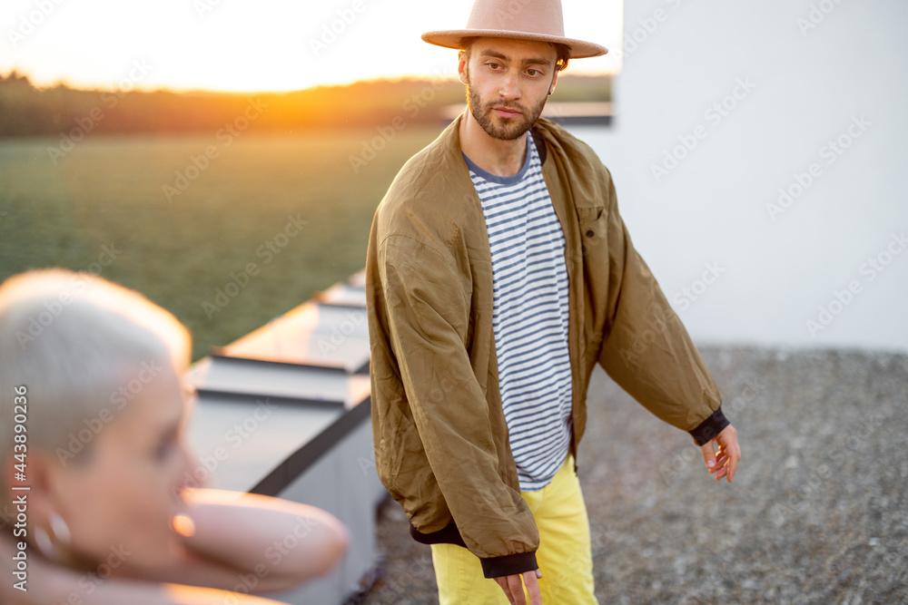 时尚无忧无虑的男人，穿着外套，日落时和朋友在屋顶上闲逛