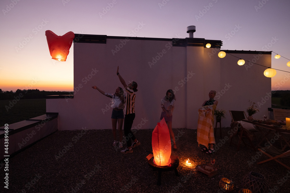 年轻人在屋顶露台上的派对上发射天灯。浪漫而有趣的夏日时光