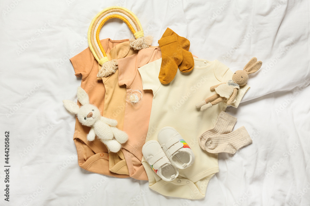 一套婴儿衣服，床上有鞋子、玩具和奶嘴