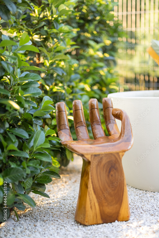绿色树篱旁的手形木制扶手椅。花园中平静而放松的角落。