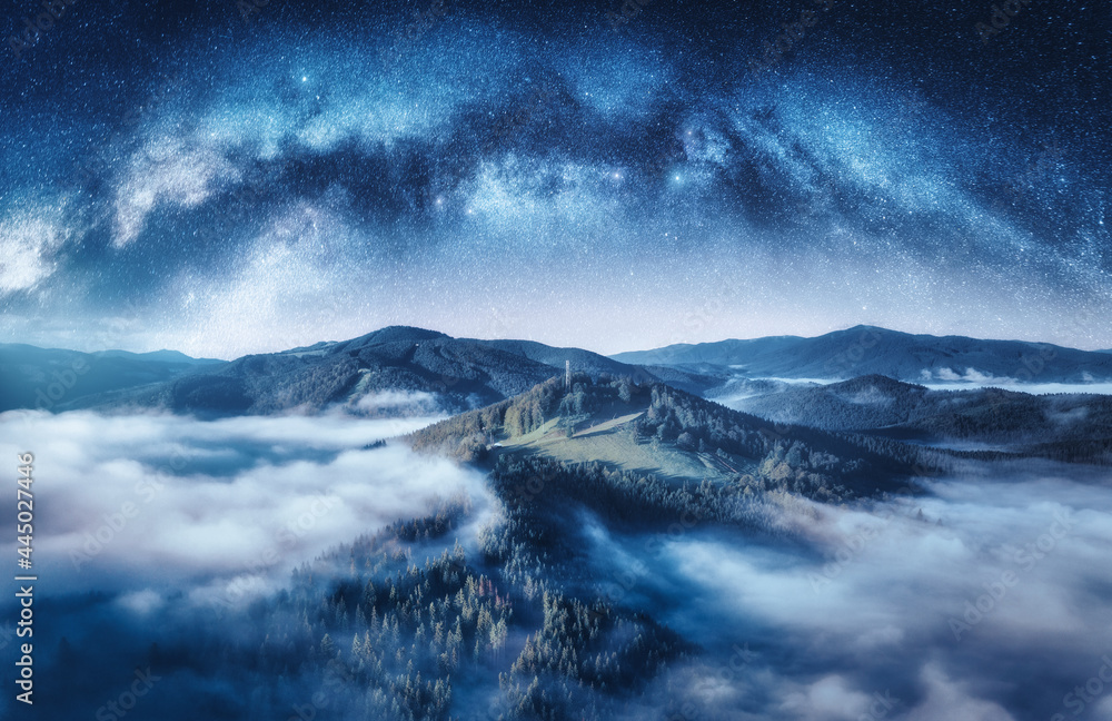 夏日星夜，银河拱门和低云中的山脉。星空景观，
