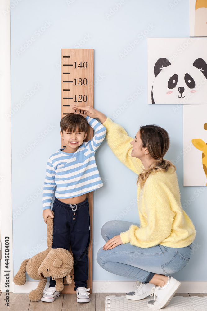 妇女在家测量小儿子的身高