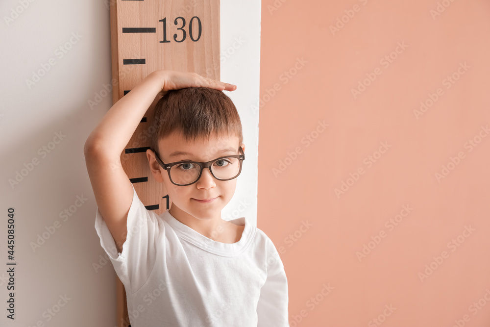 小男孩在彩色墙附近测量高度
