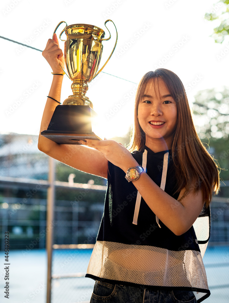 穿着运动服的亚洲少女在户外举起奖杯