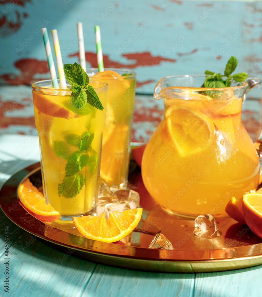 一杯柠檬水，配柠檬、橙子和薄荷叶，蓝色木底。夏季冷饮