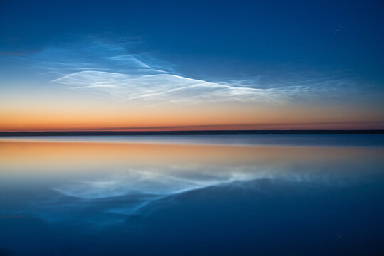 夜光云在夜空的背景上反射在湖水中，自然