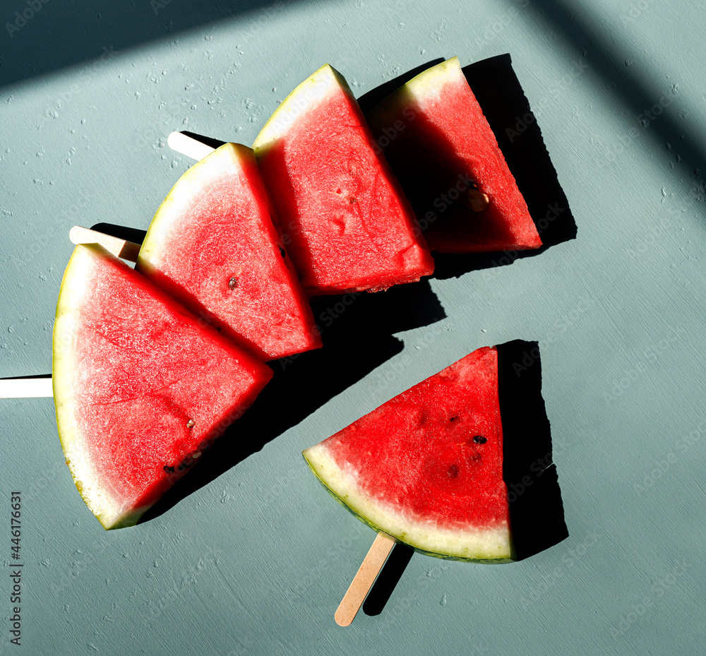 Sliced watermelon on blue background. Watermelon under direct sun shine. Top view flat lay.