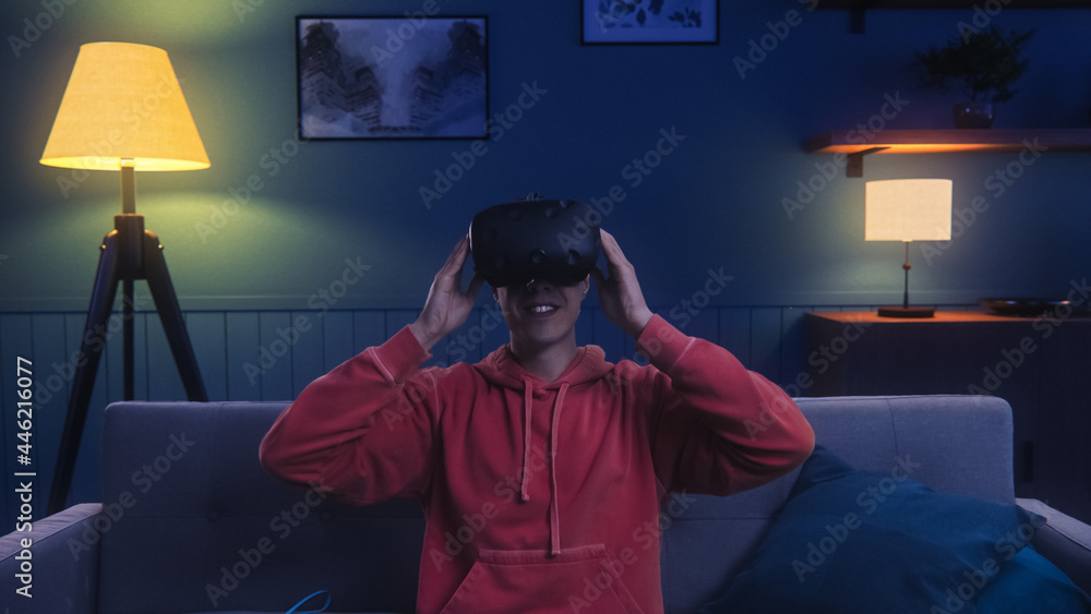 Futuristic Concept: Person Sitting on Couch and Putting on Virtual Reality Headset to Enter Cyberspa