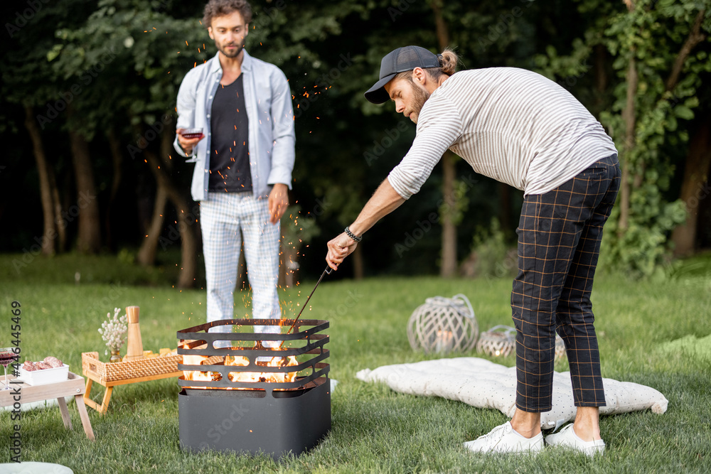 两个家伙在烧烤中生火，准备在ev森林附近的绿色草坪上野餐