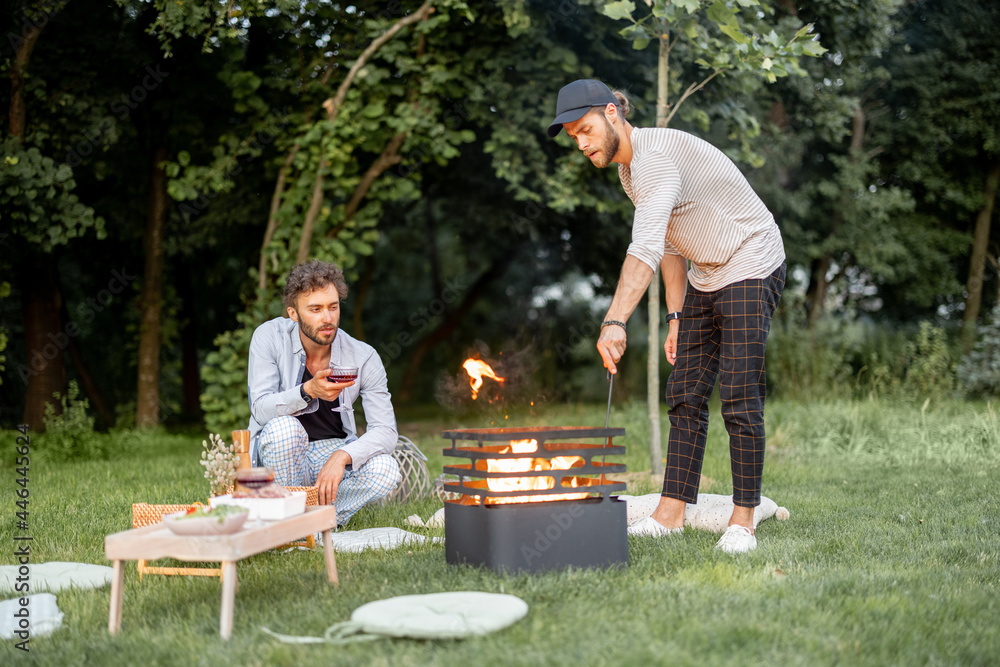 两个家伙在烧烤中生火，准备在ev森林附近的绿色草坪上野餐