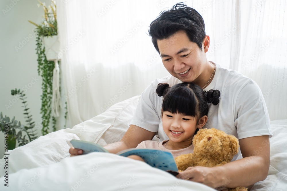 亚裔父母在家里的卧室里和小女儿一起度过休闲时光。