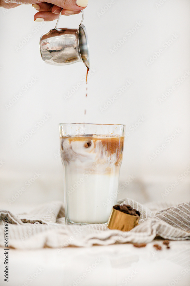 女性手倒新鲜浓缩咖啡并制作冰拿铁咖啡