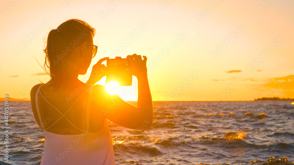 特写：在扎达尔度假的年轻女子正在拍摄日落照片。