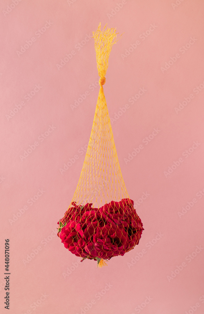 用一束红玫瑰装在黄色网袋里，粉色背景，创意十足。迷你
