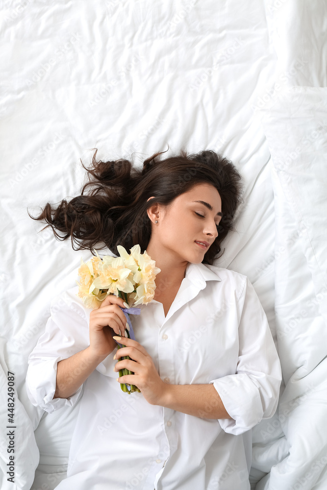 躺在床上的年轻女子，手里拿着一束美丽的水仙