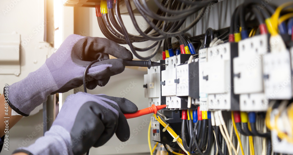 Electrician engineer tests electrical installations and wires on relay protection system. Adjustment