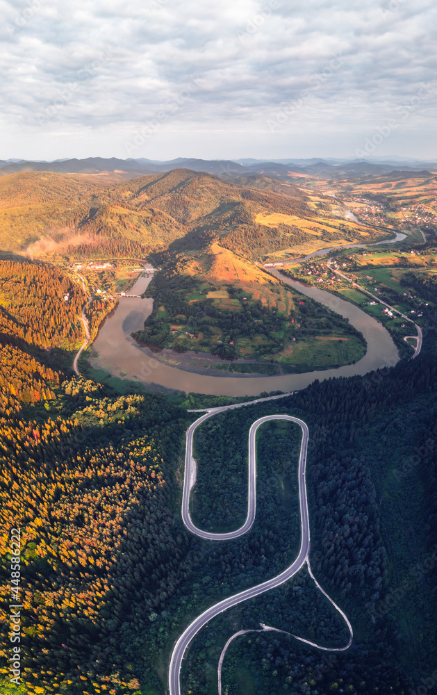Flight over the autumn mountains with mountain road serpentine